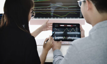 An investment expert points a pen at a tablet monitor to analyze the stock market to teach you how to make a profit.