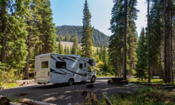Beautiful campsite in the mountains with an RV and wooden bench.