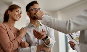 Close-up of real estate agent giving new house keys to a couple.