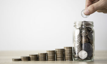 Hand putting coin to saving jar and coins stacking. Money saving