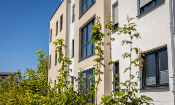 modern-residential-building-exterior-with-green-foliage-clear-blue-sky