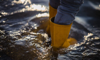 person in blue denim jeans and yellow boots standing on water