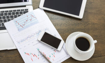 Laptop, tablet , smartphone and coffee cup with financial docume