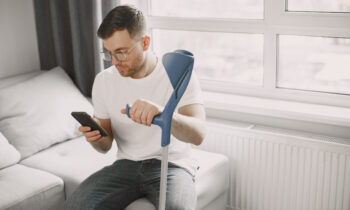 Young man with walking stick talk by phone indoors